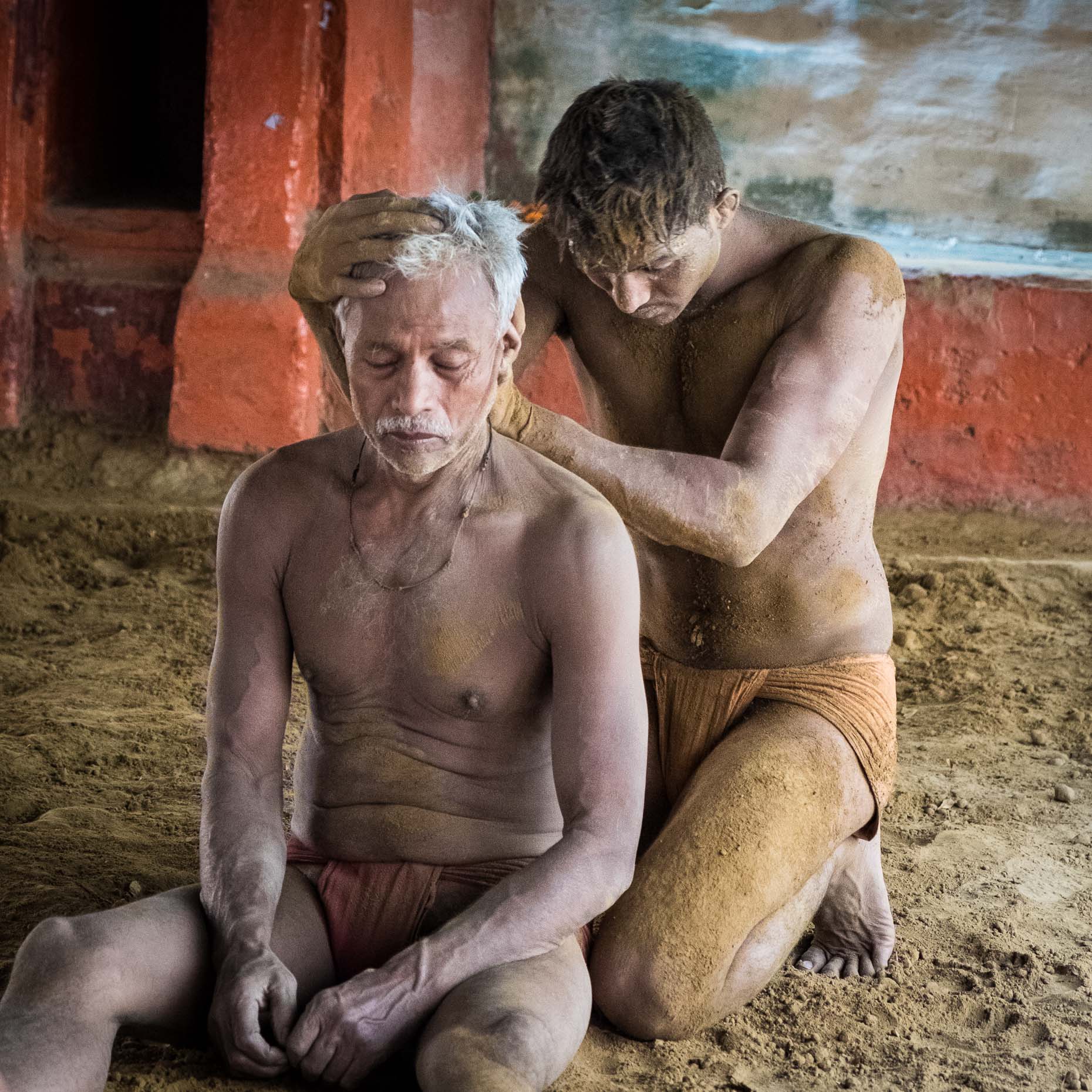 HEALING HANDS: a wrestling student massages his mentor after practice in Varanasi, India